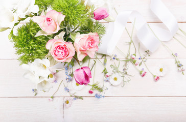 Bouquet of roses, anemones and freesias, delicate pink flowers and white ribbon on wooden board. Overhead top view, flat lay. Copy space. Birthday, Mother's, Valentines, Women's, Wedding Day concept