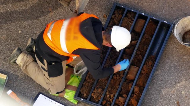 Drilling rig team workers. Modern technologies. Exploration drilling. Man examining soil samples and sorting it into small cellophane bags. Work is in process. Power and energy