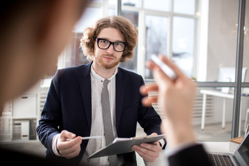 Young man with document looking at camera during meeting or appointment with client