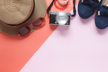 Table top view accessory of clothing women plan to travel in holiday background.Beauty & Fashion concept.Flat lay of camera with many essential items costume and sun glasses on modern pink paper.