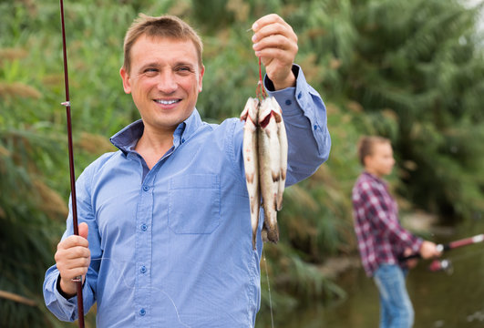Fisherman holding catch freshwater fish on river