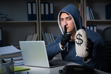Young hacker hacking into computer at night