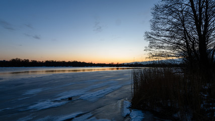 colorful winter sunset on frozen river ice