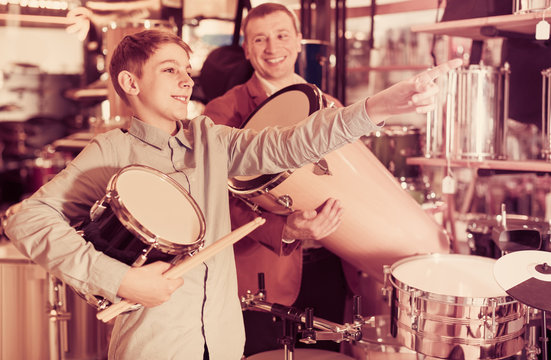 teenager and father deciding on ethnic drum in musical shop