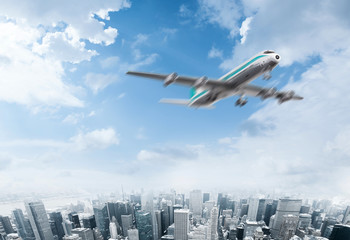 Fototapeta na wymiar Plane flying over the sky of a modern city