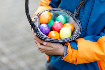 Close-up of hands of little child with colorful Easter eggs in basket