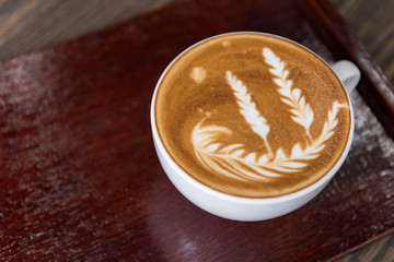 Hot coffee latte art cup with plate on wooden table