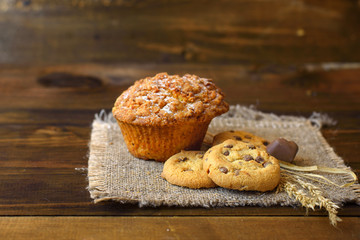 cupcake and cookies with chocolate on dark wooden background