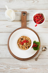 Summer healthy breakfast for two person of granola, muesli with milk jug with red currant decor on wooden board. Top view.