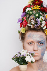 A young woman with flowers on her head and hands. Spring image with flowers. The girl and the blooming haircuts and brocade on her face.