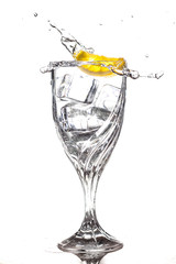 Lemon slice splashing into glass of water