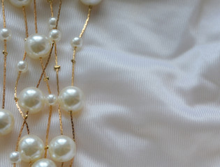 beautiful delicate luxurious elegant background.Golden threads with white pearls on white satin