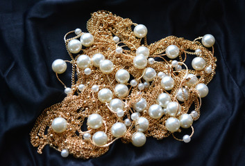 gold and pearls on a black satin close-up isolated, wealth, luxury