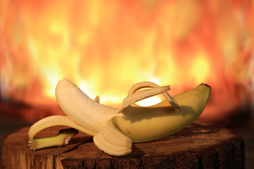 Banan przy ogniu kominka na drewnianej kłodzie. - obrazy, fototapety, plakaty