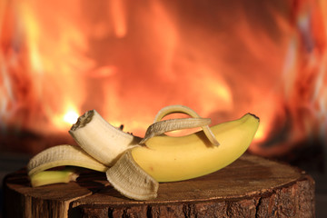 Nagryziony banan przy ogniu kominka. - obrazy, fototapety, plakaty