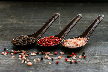 Close up pink himalayan salt and peppers in spoons