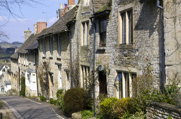 Fototapeta na wymiar Quaint Cotswold cottages in early spring sunshine on The Hill, Burford, Oxfordshire, UK