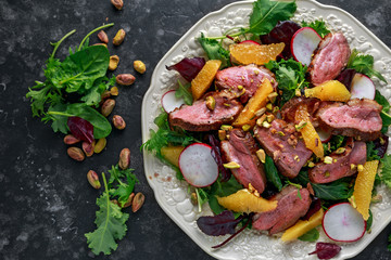 Duck breast fillets steak salad with orange halves, radishes and crushed pistachios