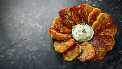 Potato pancakes, draniki, hash browns or fritters served with fresh cream and spring onion - obrazy, fototapety, plakaty