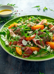 Fresh Peach salad with Parma ham, feta cheese and vegetables in a green plate. healthy food