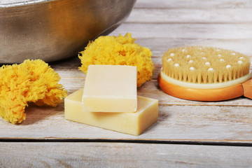 natural gray soap next to a grandmother's metal bowl with salt for a bath with a natural sponge brush and a comb with a free space for text