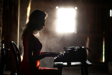 A girl in retro style prints on an old typewriter