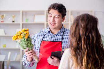 Flower shop assistant selling flowers to female customer