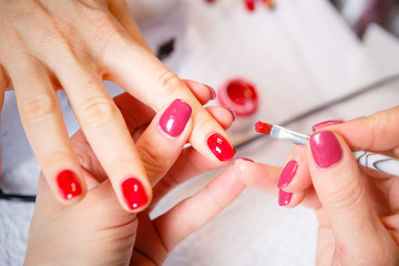 Manicure in progress - Beautiful manicured woman's nails with red nail polish. The industry of beauty and nail care, beauty salons