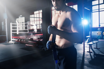 Boxer applying hand wraps while preparing for training in gym
