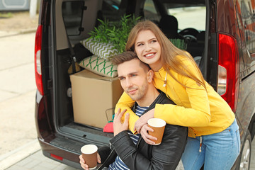 Young couple having break near their car on moving day