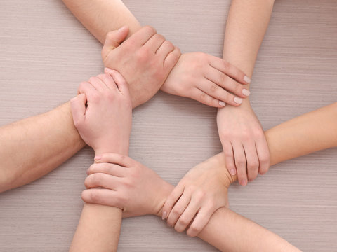Group of people making circle with their hands on wooden background. Unity concept