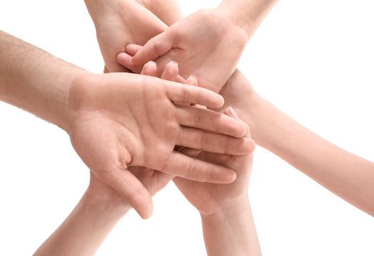 Young people putting hands together as symbol of unity, on white background
