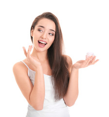 Young woman applying face cream on white background