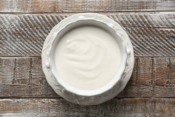 Tasty yogurt in dish on wooden table