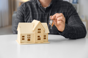 Man holding key near house model, closeup