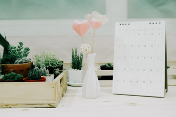 front view. valentine day background heart and vase with plant and calendar placed on wooden table. image for idea, love, celebration, workplace, copy space, decoration concept