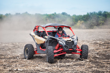 Smiling man at the wheel of quad bike standing in the field © alexlukin