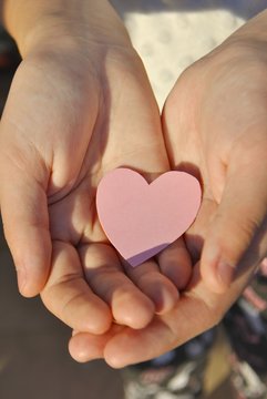 Pink paper heart on the girl's hands