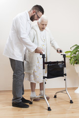 8.	Seniorka w białym szlafroku i koszuli nocnej idzie przy pomocy chodzika. Pielęgniarz podtrzymuje i asekuruje starą kobietę.