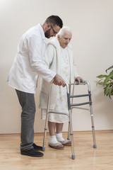 Balkonik medyczny rehabilitacyjny. Babcia uczy się chodzić przy pomocy balkonika i w asyście pielęgniarza. - obrazy, fototapety, plakaty