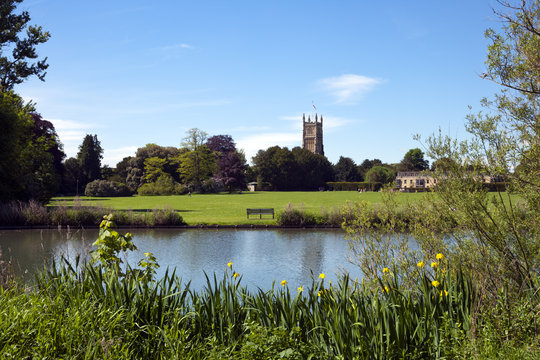 Tower of the landmark Abbey Church seen across Abbey Grounds in spring sunshine, Cirencester, The Cotswolds, Gloucestershire, UK