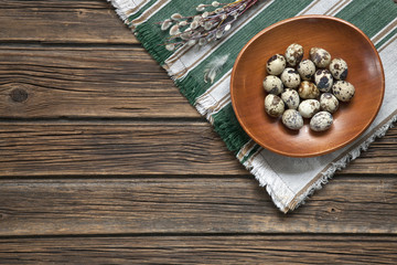Quail eggs on a plate. Easter serving of the festive table. Top view, space for your text on a rustic wooden background