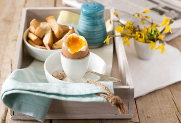Breakfast from soft-boiled egg, bread toast, coffee with cream and fresh newspaper.