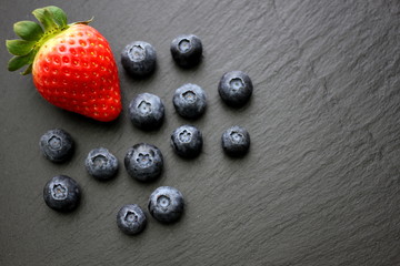 Strawberries and blueberries on slate background