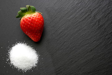 Strawberry with crystal sugar on slate background