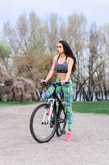 a young girl goes in for sports in the fresh air . Sports clothing pink color , sitting on the bike