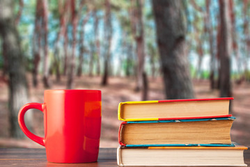 red cup and herd with books on the background of the forest