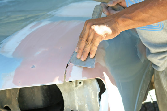 Automotive paint technician using paint on putty knife at bonnet , A part of the procedure to paint a new bonnet.