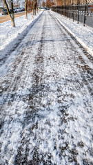 Close-up of asphalt in the snow. Road in the city in the winter, cleaned snow cleaned the street from the snow in the park.