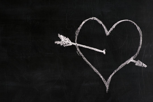 white chalk heart with arrow on black background